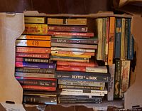 Top view of box showing spines of approximately fifty assorted books in paperback and hardcover formats