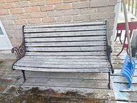 Front view of wooden slat garden bench against brick wall