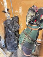 Two golf bags with clubs leaning against wall
