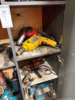 Cabinet right side top and middle shelves showing yellow hammer drill, heat gun, die grinder, angle grinder, belt sander