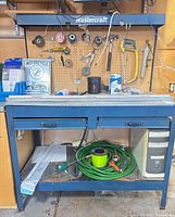 Full view of Mastercraft workbench, pegboard, contents on top and shelf