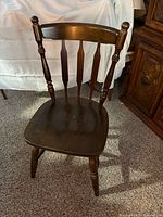 Full view of the wooden spindle-back chair showing seat, backrest and legs