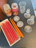 Entire lot showing jar candles, tapers in box, loose tapers, short crystal holders, tall crystal candlesticks and cream votive holder partially visible