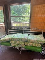 White metal sofa frame with stacked green floral cushions