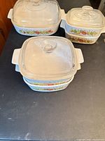 Three sizes of white Spice of Life casserole dishes with lids stacked and grouped