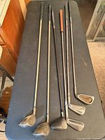 Six golf clubs laid out showing heads and shafts