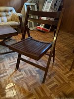 Front view of wooden folding chair showing slatted seat and brown finish
