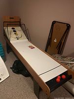 Front angled view of skee ball table showing play surface, scoring rings, protective net, and balls