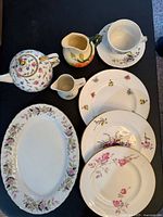 All items arranged on table: teapot, two creamers, teacup and saucer, three plates, oval platter