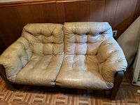 Beige leather loveseat with wood trim and tufted cushions