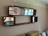 Front view of wood wall shelf showing overall design, mirror panels, and compartments