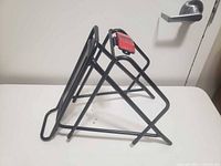 Side view of black tubular metal bicycle rear cargo rack with red reflector