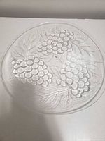 Top view of the clear glass round dish showing embossed grape clusters and leaves