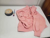 Sweater, CD spindle, paintbrush on tabletop