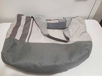 Front view of two-tone grey canvas duffel bag showing handles and stripe accents