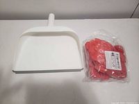 White plastic dustpan and sealed bag of red artificial flower petals on tabletop