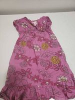 Front view of pink floral kids dress laid flat