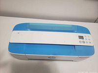 Top view of blue and white HP printer showing control panel and scanner feed