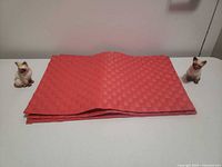 Stack of red woven placemats flanked by two Siamese cat shakers