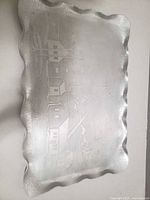 Front view of silver-tone plate showing scalloped rim and etched mining scene