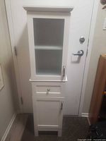 Full view of the white cabinet showing glass door, drawer, lower door and handles