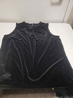 Front view of black sleeveless dress shirt laid flat