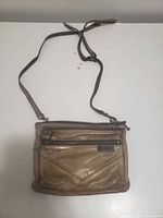 Front view showing overall purse, strap, and brand plaque
