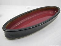 Perspective view of oval dish showing black exterior and red interior glaze