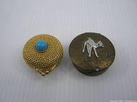 Both items side by side: Estee Lauder compact left, Japanese camel pill box right