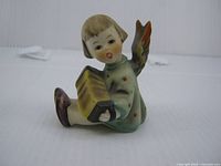 Front view of seated angel figurine holding accordion