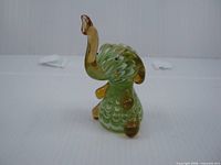 Front angled view of green and amber handblown glass elephant