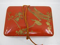 Top view showing red lacquer surface with gilt bird and plum blossom design and tie cord