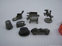 All eight metal Monopoly tokens plus two dice for scale