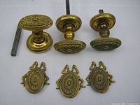 three brass door knobs with two steel spindles and three brass keyhole covers displayed on white background