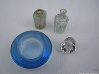 Group view of four glass items: blue dish, two clear opium bottles, Swarovski heart