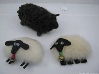 Group of three wool sheep figurines including black one and two white ornaments
