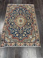 Full view of the handmade Persian Naeen rug on dark floor