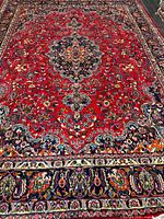 Full view of rug showing red field, borders and size perspective