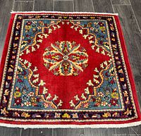 Full view of square Persian wool rug on dark floor