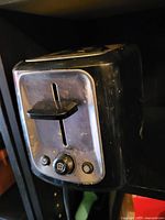Front and side view of black 2-slot toaster showing stainless front panel, lever, buttons and wear