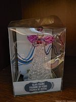 Front view of boxed clear glass angel figurine with purple wings and halo