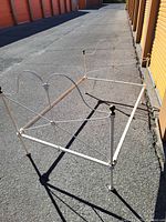 Full view of assembled cream metal full bed frame with brass finials