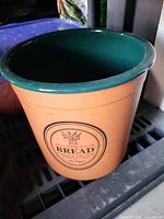 Side view of tan glazed bread crock with green interior and printed "BREAD" wreath label