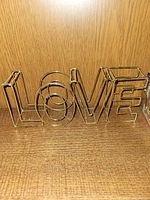 Front view of gold tone wire LOVE sculpture