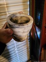 Marble mortar bowl in hand showing gray-white veining, interior wear, rim chips