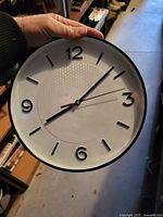 Front view of round wall clock showing face, hands, numerals, and black rim