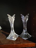 Pair of clear pressed glass candlestick holders standing on wood shelf