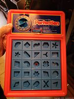 Front view of Perfection game showing timer dial and 5×5 grid