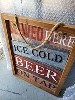 Front view of rustic wood-framed vertical sign showing text and rope hanger