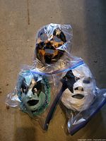 Three adult decorative masks in zipper bags: black/gold, turquoise/black with sequins, white/black